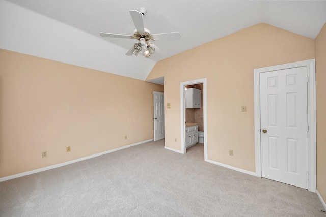 unfurnished bedroom with vaulted ceiling, light carpet, ceiling fan, and ensuite bath