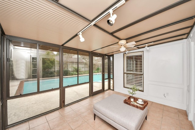 sunroom / solarium featuring rail lighting and ceiling fan