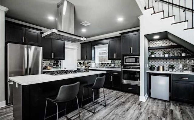 kitchen with hardwood / wood-style floors, a breakfast bar, a center island, and appliances with stainless steel finishes