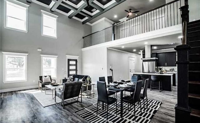 dining room featuring a towering ceiling, coffered ceiling, crown molding, dark wood-type flooring, and beam ceiling