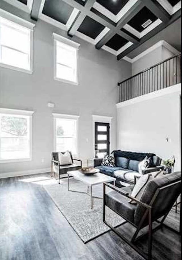 living room with coffered ceiling, a towering ceiling, hardwood / wood-style floors, and beam ceiling