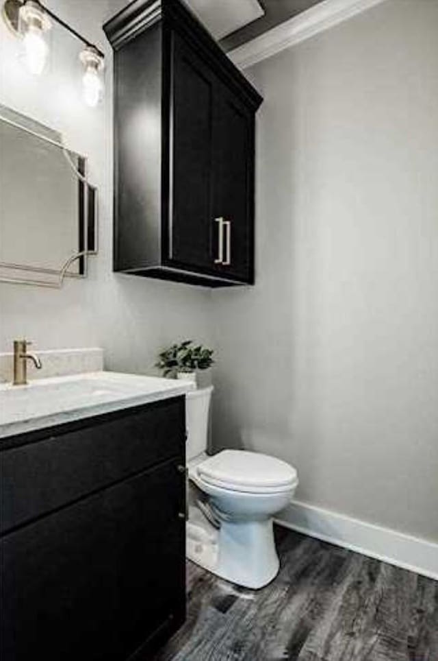 bathroom with crown molding, wood-type flooring, vanity, and toilet