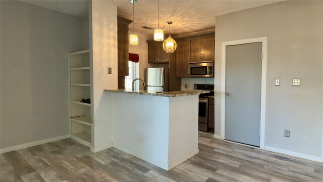 kitchen featuring hanging light fixtures, light hardwood / wood-style flooring, kitchen peninsula, stainless steel appliances, and light stone countertops