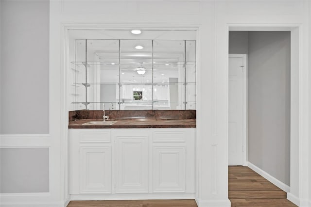 bar with dark wood-type flooring and sink