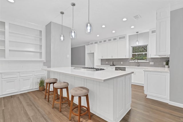 kitchen with stainless steel gas cooktop, sink, white cabinets, and light hardwood / wood-style flooring