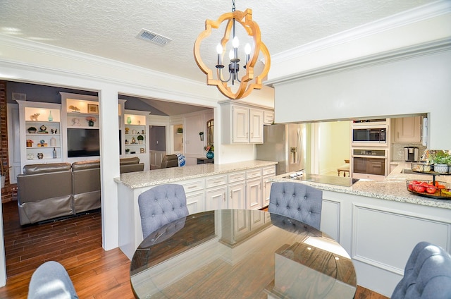 dining area with an inviting chandelier, wood-type flooring, ornamental molding, and a textured ceiling