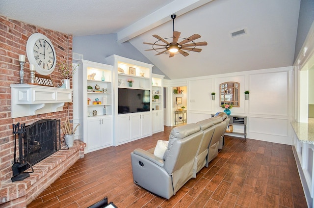 living room with dark wood-type flooring, ceiling fan, lofted ceiling with beams, and a brick fireplace