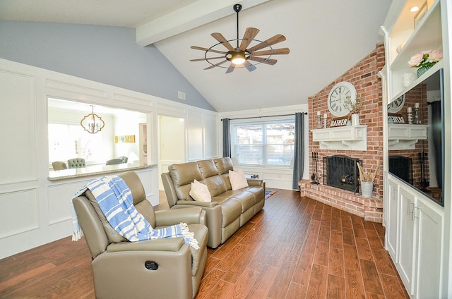 living room with dark hardwood / wood-style flooring, vaulted ceiling with beams, ceiling fan with notable chandelier, and a fireplace