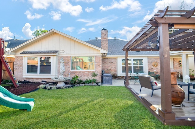 rear view of property with a yard, a pergola, a playground, and a wooden deck