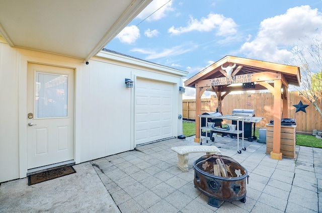 view of patio featuring a garage, a gazebo, and a fire pit