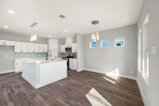 kitchen with a kitchen island with sink, white cabinetry, decorative light fixtures, and appliances with stainless steel finishes