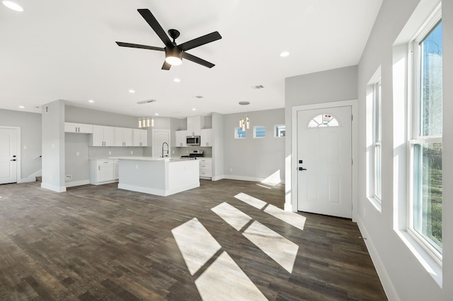 kitchen featuring white cabinetry, hanging light fixtures, dark hardwood / wood-style flooring, an island with sink, and stainless steel appliances