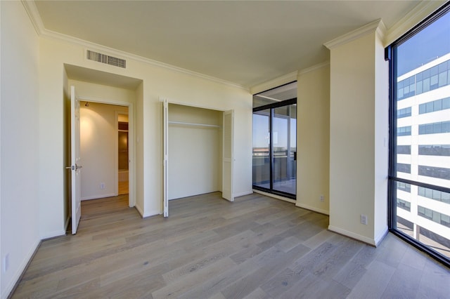 unfurnished bedroom with ornamental molding, access to outside, light wood-type flooring, and a closet