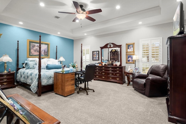 bedroom featuring a raised ceiling, light carpet, and multiple windows