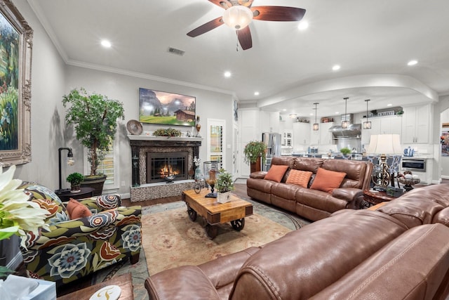 living room with wood-type flooring, ornamental molding, and ceiling fan