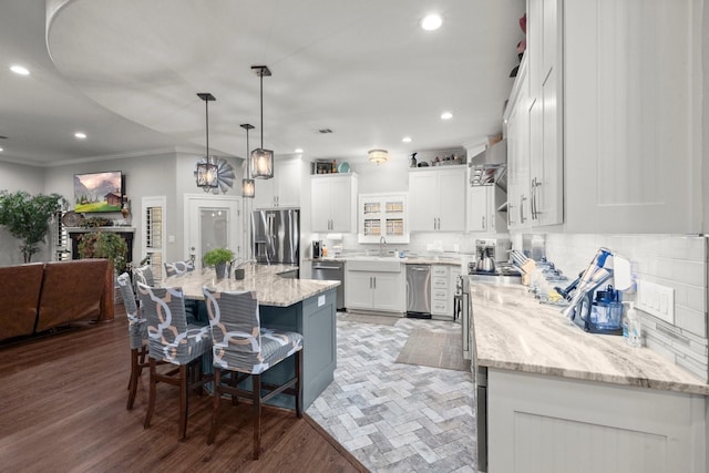 kitchen with a kitchen island, appliances with stainless steel finishes, a breakfast bar, white cabinetry, and hanging light fixtures