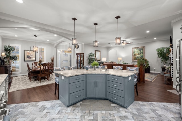 kitchen featuring hanging light fixtures, a breakfast bar area, ornamental molding, and a kitchen island