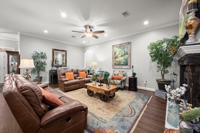 living room with crown molding, ceiling fan, a fireplace, and dark hardwood / wood-style flooring