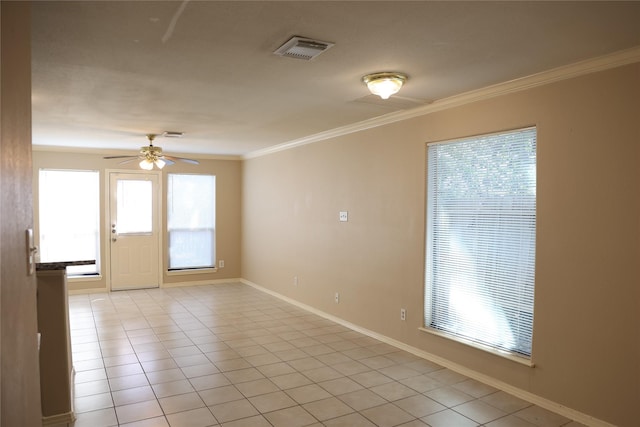 empty room with crown molding, a wealth of natural light, ceiling fan, and light tile patterned floors