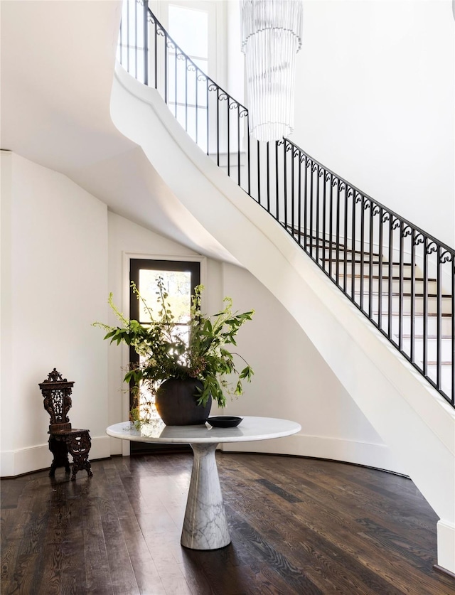 staircase with hardwood / wood-style flooring, a towering ceiling, and a chandelier