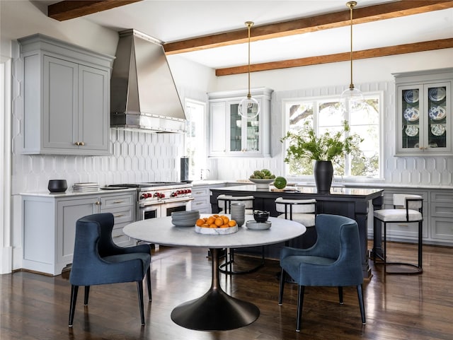 kitchen with gray cabinets, hanging light fixtures, wall chimney range hood, and range with two ovens