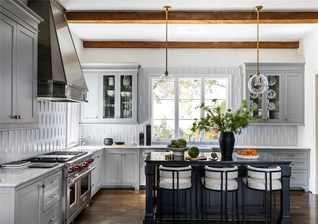 kitchen featuring a breakfast bar area, double oven range, dark hardwood / wood-style floors, decorative light fixtures, and exhaust hood