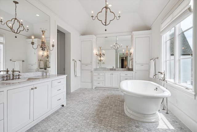 bathroom with vaulted ceiling, a bath, a notable chandelier, and vanity