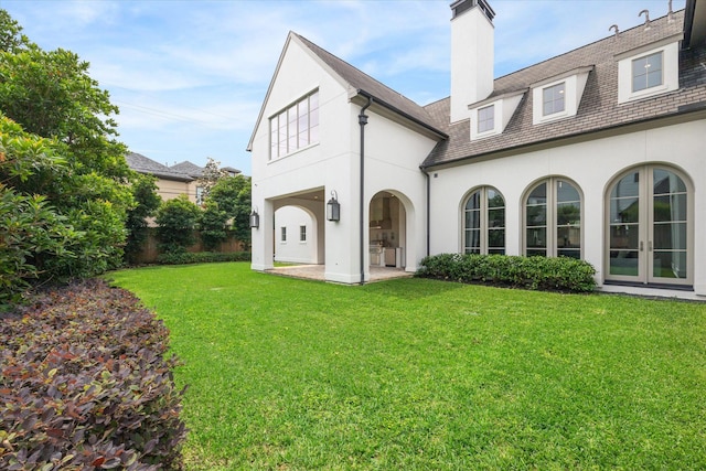 rear view of house featuring a lawn and french doors