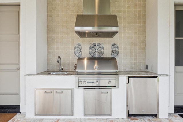 kitchen featuring backsplash, stainless steel fridge, sink, and wall chimney range hood