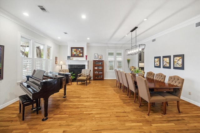 dining room with crown molding, an inviting chandelier, and light hardwood / wood-style flooring