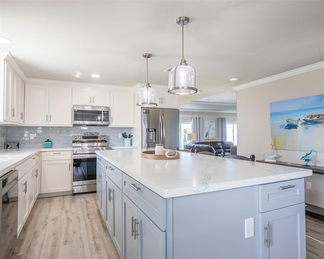 kitchen featuring stainless steel appliances, white cabinetry, hanging light fixtures, and ornamental molding