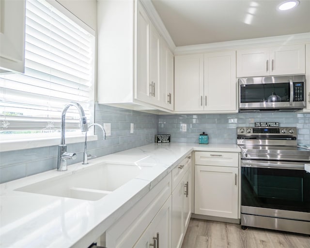 kitchen featuring sink, stainless steel appliances, light stone countertops, white cabinets, and decorative backsplash