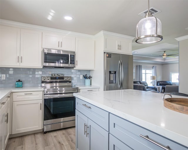 kitchen with white cabinetry, hanging light fixtures, ceiling fan, stainless steel appliances, and light hardwood / wood-style flooring