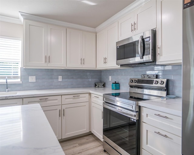 kitchen featuring appliances with stainless steel finishes, sink, white cabinets, and backsplash