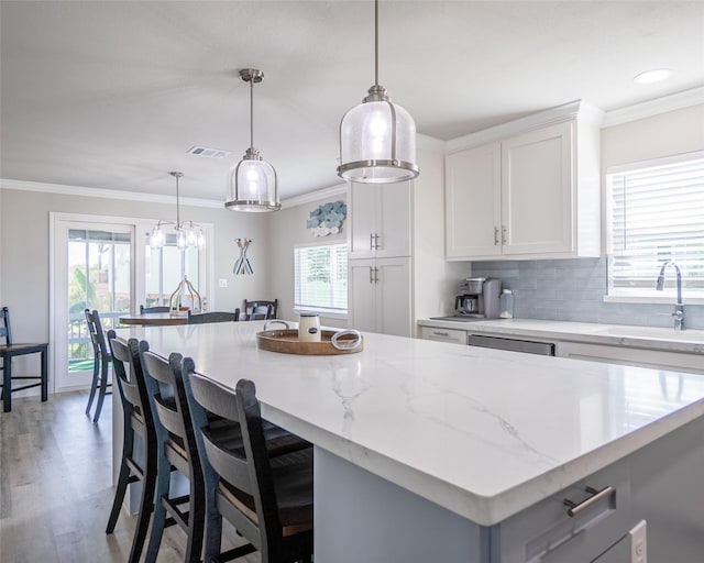 kitchen featuring white cabinetry, sink, pendant lighting, and a center island