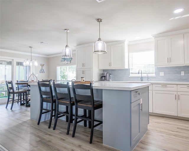 kitchen with hanging light fixtures, white cabinetry, a center island, and a kitchen breakfast bar