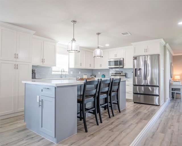 kitchen featuring pendant lighting, white cabinetry, decorative backsplash, a center island, and stainless steel appliances