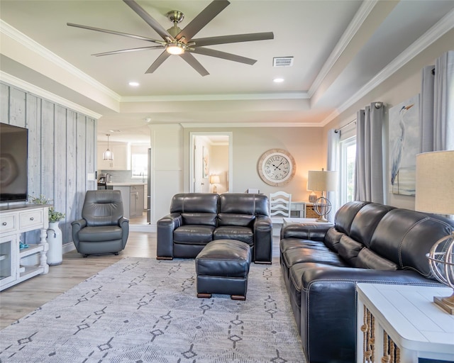 living room featuring ornamental molding, ceiling fan, light hardwood / wood-style floors, and a tray ceiling