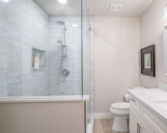 bathroom featuring tiled shower, wood-type flooring, toilet, and vanity