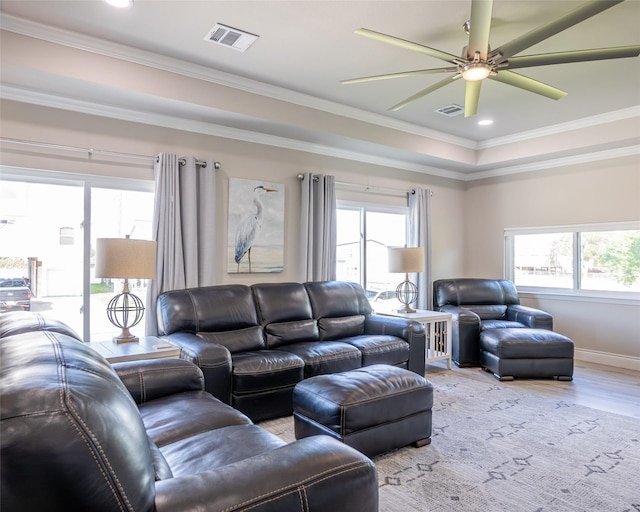 living room with crown molding, plenty of natural light, ceiling fan, and light wood-type flooring