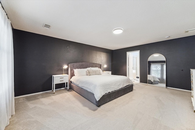 bedroom with ensuite bath and light colored carpet