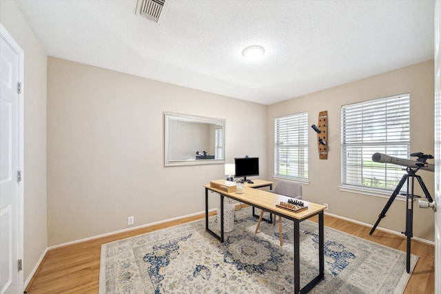 office with light hardwood / wood-style floors and a textured ceiling