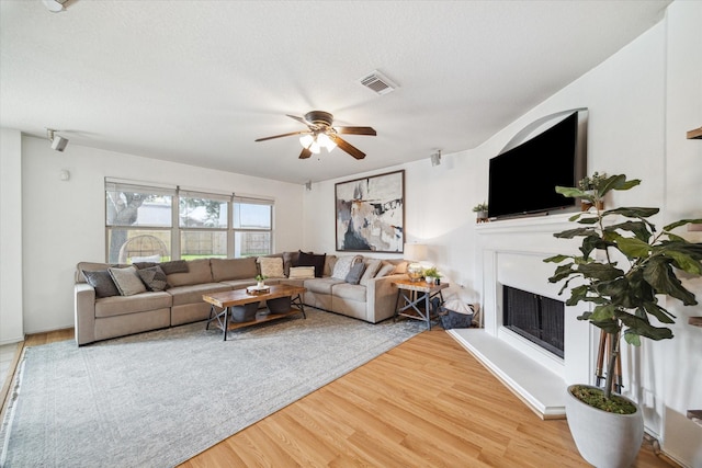 living room featuring a textured ceiling, ceiling fan, and wood-type flooring