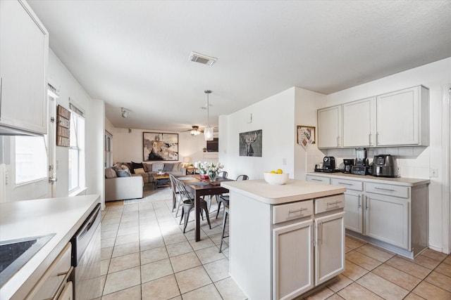 kitchen featuring light tile patterned floors, sink, a kitchen island, decorative light fixtures, and stainless steel dishwasher