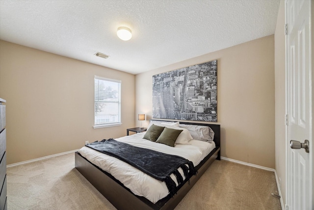 bedroom with a textured ceiling and light colored carpet