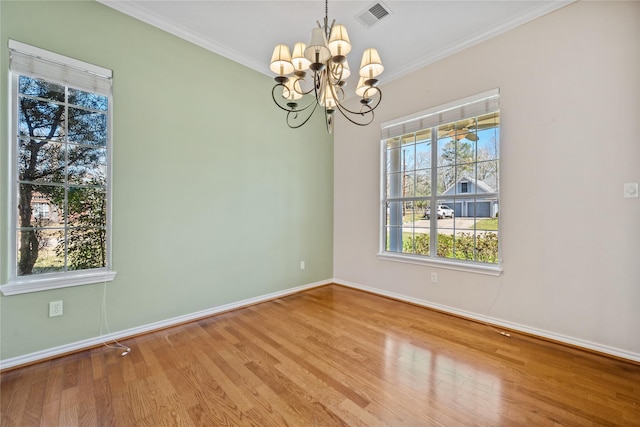 empty room with wood finished floors, visible vents, baseboards, ornamental molding, and an inviting chandelier