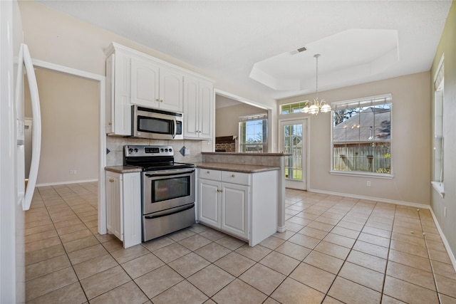 kitchen featuring light tile patterned floors, tasteful backsplash, visible vents, a raised ceiling, and appliances with stainless steel finishes