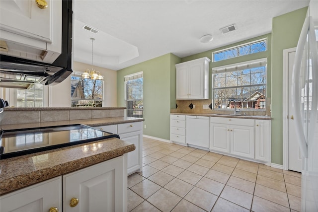 kitchen featuring visible vents, backsplash, white cabinets, white dishwasher, and a sink