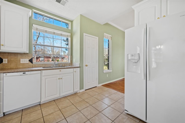 kitchen with visible vents, white cabinetry, a sink, light tile patterned flooring, and white appliances