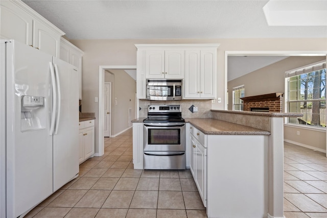 kitchen featuring appliances with stainless steel finishes, a healthy amount of sunlight, light tile patterned flooring, and backsplash